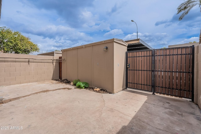 view of outbuilding featuring fence and a gate