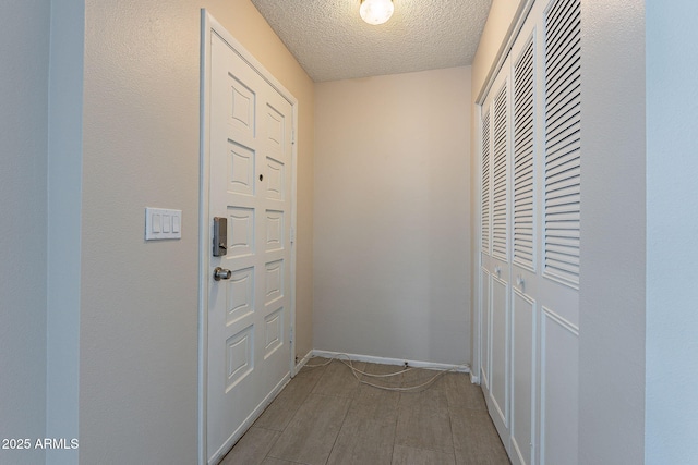 doorway to outside with a textured ceiling and baseboards