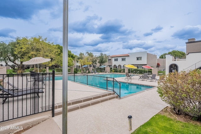 community pool with fence and a patio area