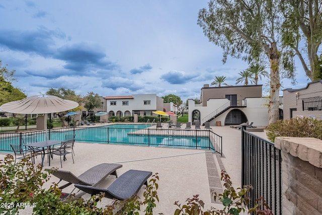 community pool with a patio and fence