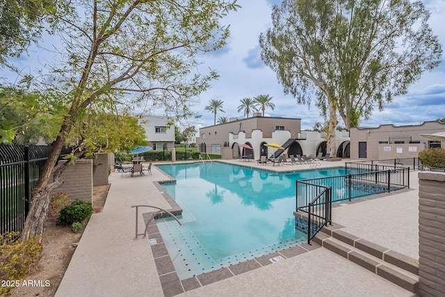 pool with a patio area and fence