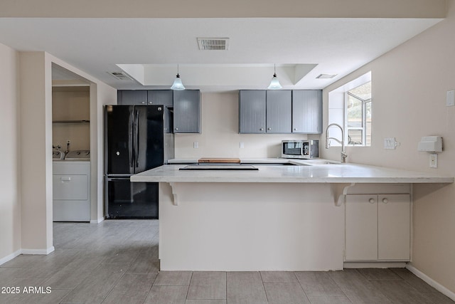 kitchen with visible vents, washing machine and dryer, freestanding refrigerator, a peninsula, and a raised ceiling