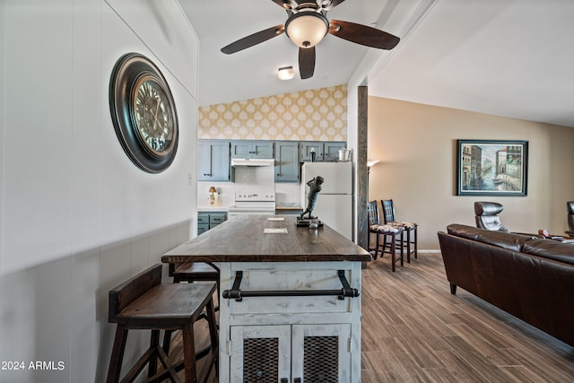 kitchen with white appliances, ceiling fan, lofted ceiling, dark wood-type flooring, and a breakfast bar