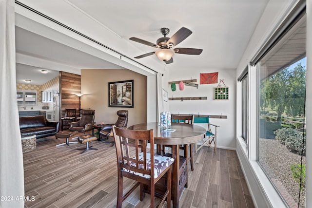 dining space with hardwood / wood-style floors, wood walls, and ceiling fan