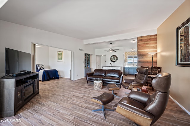 living room featuring wood-type flooring, ceiling fan, and wooden walls