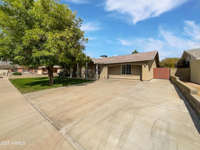 view of front of home featuring a gate, fence, driveway, stucco siding, and a front lawn