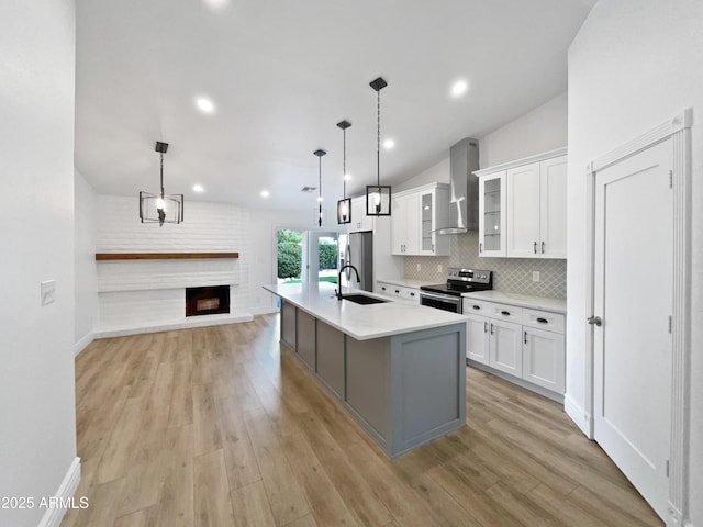 kitchen with a sink, wall chimney exhaust hood, white cabinetry, and stainless steel appliances