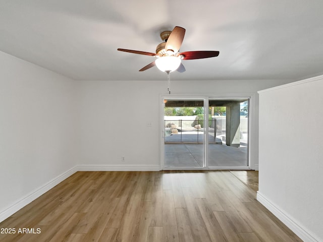 spare room featuring baseboards, wood finished floors, and a ceiling fan