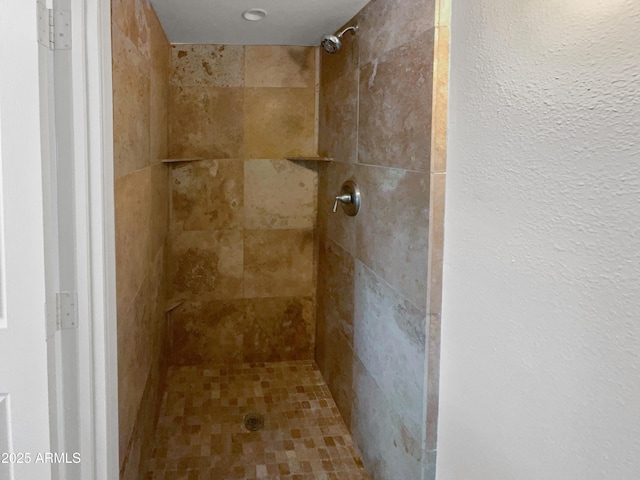 full bathroom with tiled shower and a textured wall