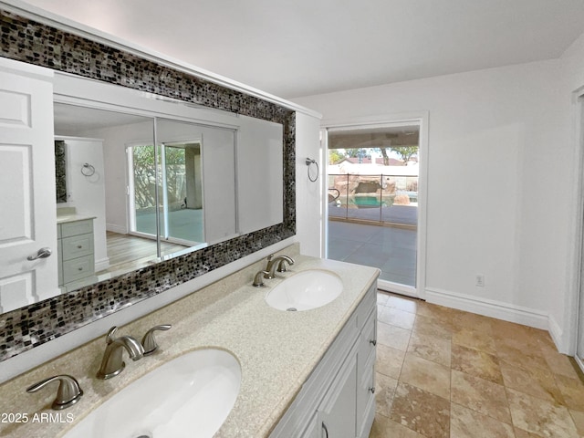 bathroom with a sink, baseboards, and double vanity