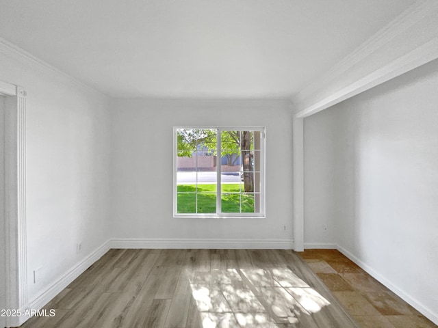 empty room with wood finished floors, baseboards, and ornamental molding