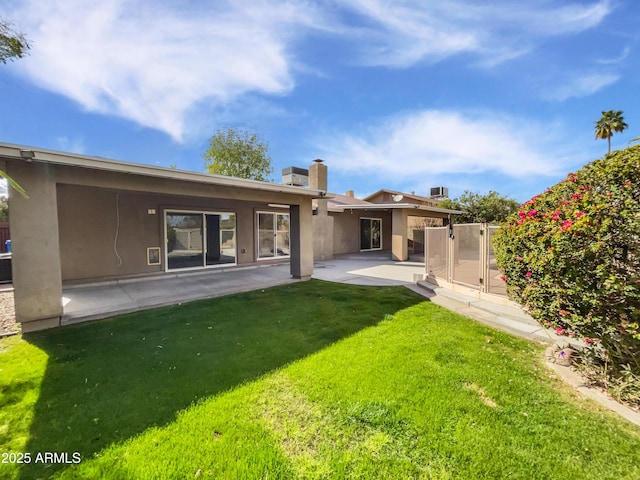 back of house featuring stucco siding, fence, a lawn, and a patio area