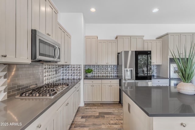 3806 E Taurus Pl, Chandler, AZ 85249 - kitchen with stainless steel appliances, dark countertops, wood finished floors, backsplash, and recessed lighting