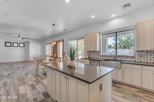 3806 E Taurus Pl, Chandler, AZ 85249 - kitchen featuring dark countertops, stainless steel dishwasher, a sink, cream cabinets, and light wood-style floors