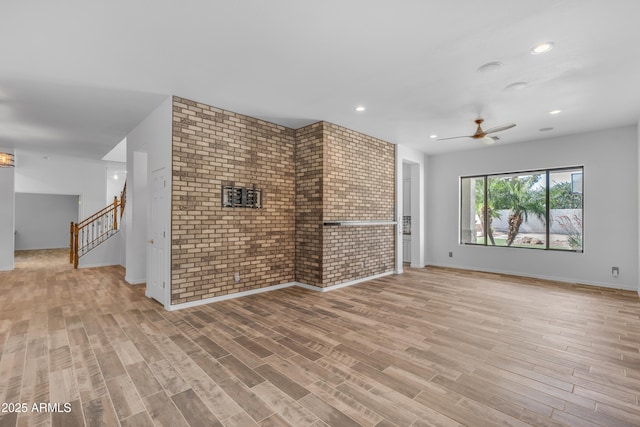 3806 E Taurus Pl, Chandler, AZ 85249 - unfurnished living room with brick wall, a ceiling fan, light wood finished floors, stairs, and baseboards