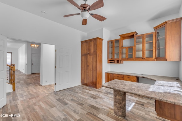 3806 E Taurus Pl, Chandler, AZ 85249 - kitchen with brown cabinets, glass insert cabinets, a chandelier, light wood-style floors, and ceiling fan