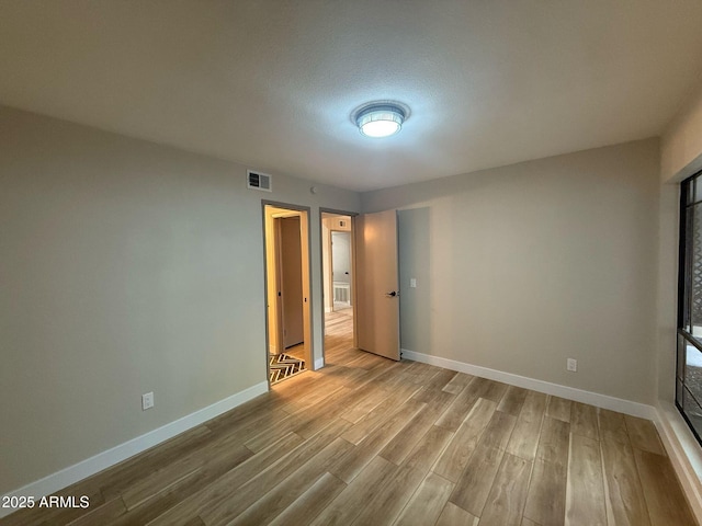 interior space featuring baseboards, wood finished floors, and visible vents