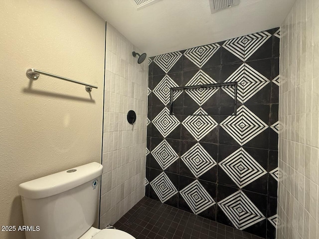 bathroom with visible vents, a tile shower, and toilet