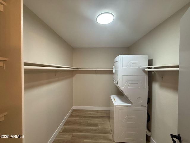 spacious closet with stacked washer / drying machine and wood finished floors