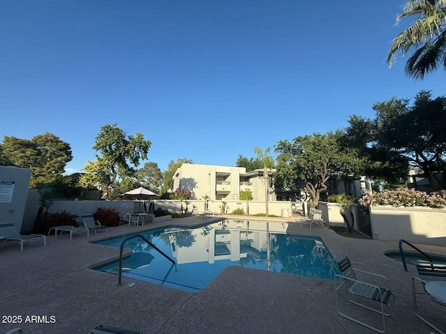 pool with a patio area and fence