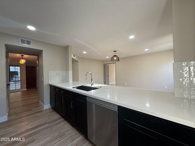 kitchen featuring stainless steel dishwasher, a sink, recessed lighting, and dark cabinets