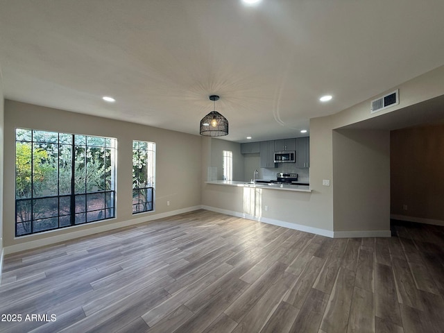 unfurnished living room featuring baseboards, recessed lighting, wood finished floors, and visible vents