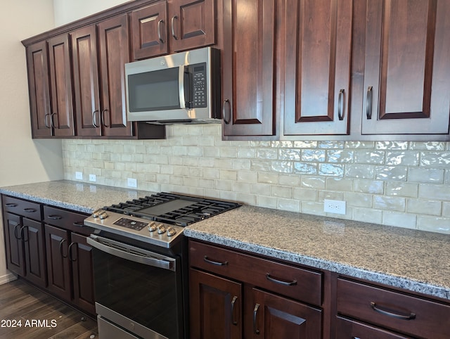 kitchen featuring light stone counters, appliances with stainless steel finishes, dark brown cabinetry, dark hardwood / wood-style flooring, and decorative backsplash