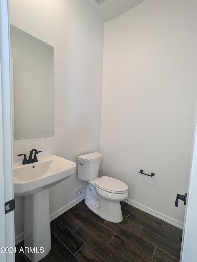 bathroom with toilet, sink, and wood-type flooring