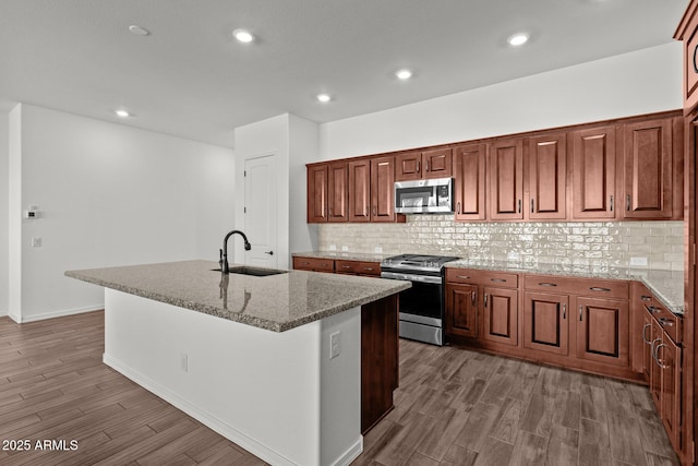 12308 W Parkway Ln, Avondale, AZ 85323 - kitchen featuring appliances with stainless steel finishes, a sink, wood finished floors, a center island with sink, and decorative backsplash