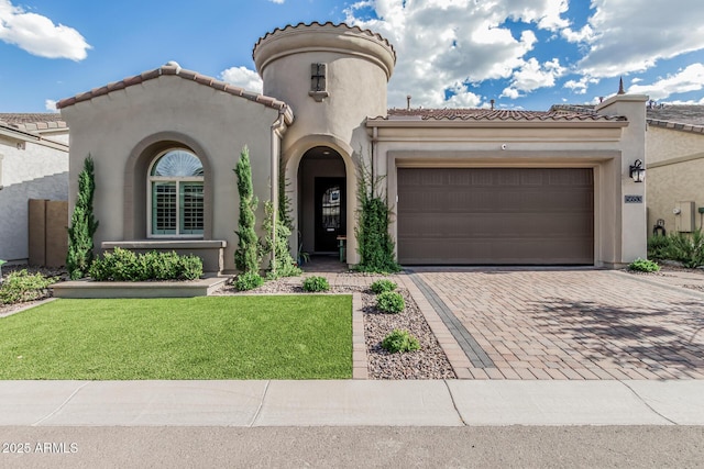 mediterranean / spanish house featuring an attached garage, decorative driveway, a front lawn, and stucco siding
