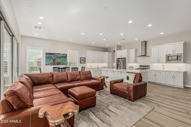 living room with recessed lighting, light wood-style flooring, and visible vents