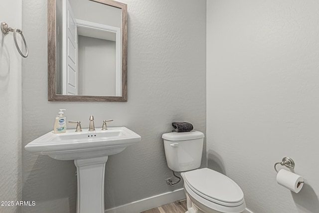bathroom featuring baseboards, toilet, and wood finished floors