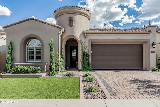 mediterranean / spanish house featuring a tiled roof, a garage, decorative driveway, a front lawn, and stucco siding