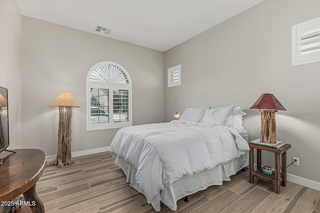 bedroom featuring baseboards, light wood-type flooring, and visible vents