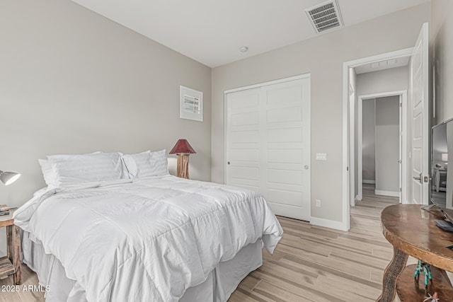 bedroom with visible vents, light wood finished floors, baseboards, and a closet