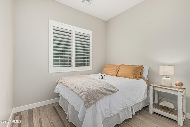 bedroom featuring baseboards, wood finished floors, and visible vents