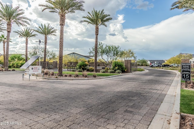 view of street featuring a gated entry and curbs