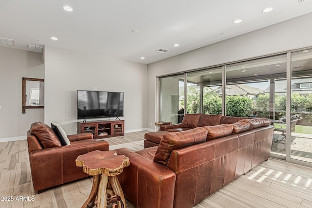 living room with visible vents, light wood finished floors, and a wealth of natural light
