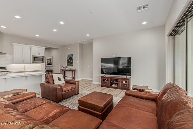 living area featuring visible vents, recessed lighting, baseboards, and light wood-type flooring