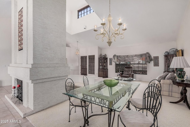 dining area featuring a chandelier, tile patterned flooring, a fireplace with raised hearth, and a high ceiling