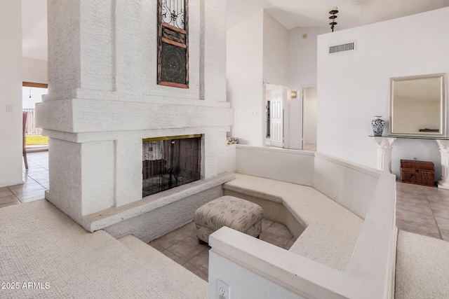 interior space with tile patterned flooring, a fireplace, visible vents, and high vaulted ceiling