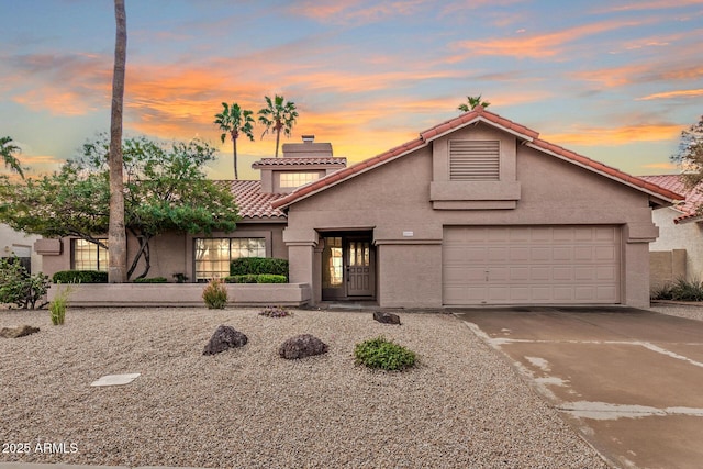 view of front of house featuring a tiled roof, a garage, driveway, and stucco siding