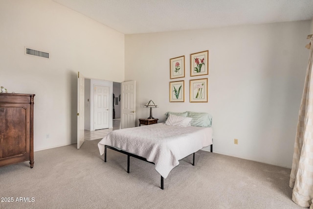 bedroom with light colored carpet, visible vents, and high vaulted ceiling