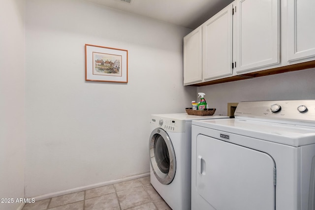 laundry area featuring washer and dryer, light tile patterned flooring, cabinet space, and baseboards