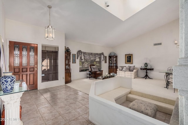 carpeted foyer entrance with tile patterned floors, visible vents, lofted ceiling, and a chandelier