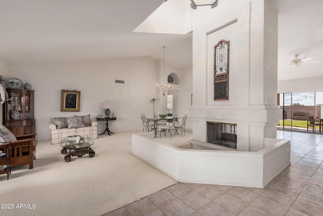 tiled living area featuring visible vents, carpet floors, high vaulted ceiling, and ceiling fan with notable chandelier