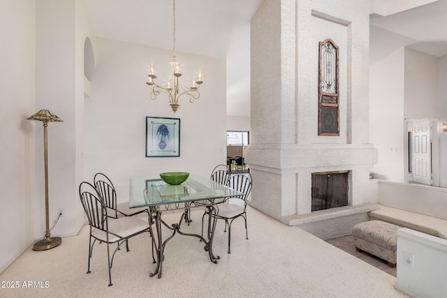 carpeted dining area featuring a chandelier, a fireplace, and a towering ceiling