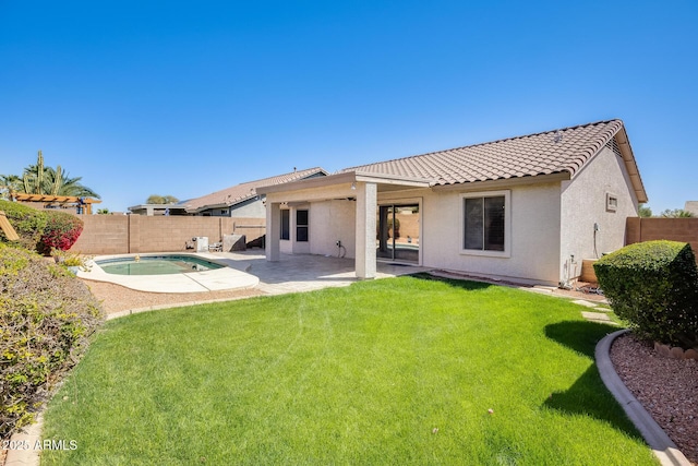 rear view of house featuring a patio area, a tiled roof, a yard, and a fenced backyard