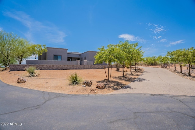 pueblo-style house with driveway, fence, and stucco siding