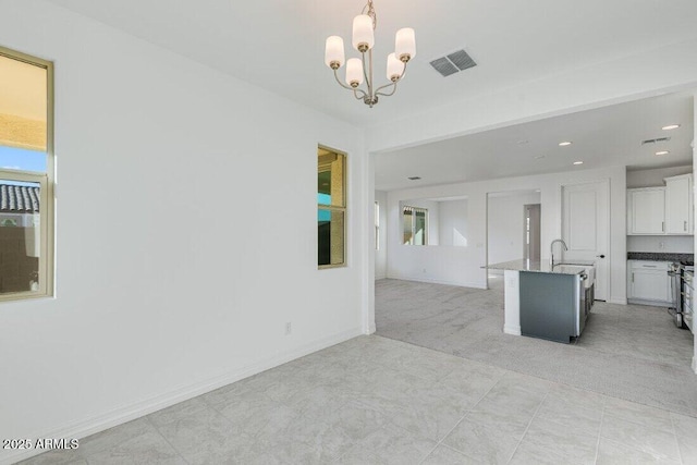 unfurnished living room featuring recessed lighting, light colored carpet, visible vents, a chandelier, and baseboards